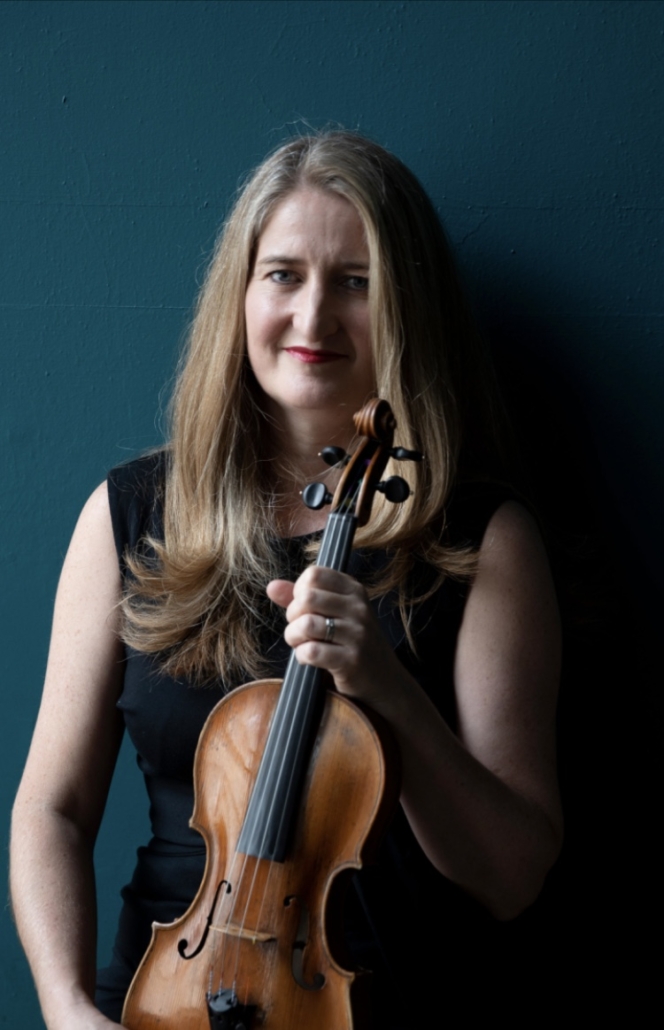 A white woman with long brown hair wearing a black dress and holding a violin.