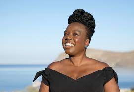 A black woman wearing a black dress stood next to the sea.